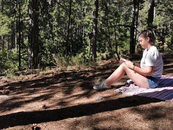 Young woman reading a book in the forest