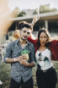 Portrait of woman dancing while standing with friend having drink at concert