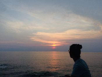 Man looking at sea against sky during sunset