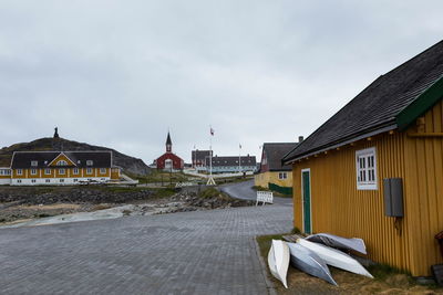 Grey and white kayaks resting against mustard colored house in the old part of nuuk, greenland,