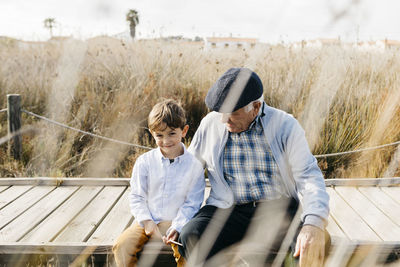 Grandfather sitting with his grandson on boardwalk relaxing