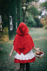 Rear view of girl holding basket on field