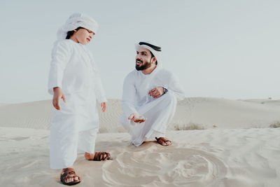 Father and son enjoying while crouching in desert