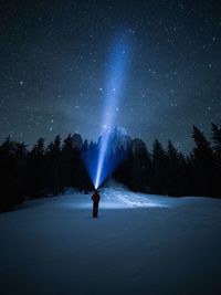Full length of person holding flash light while standing on snow covered field