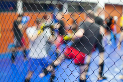 Men playing in court seen through chainlink fence