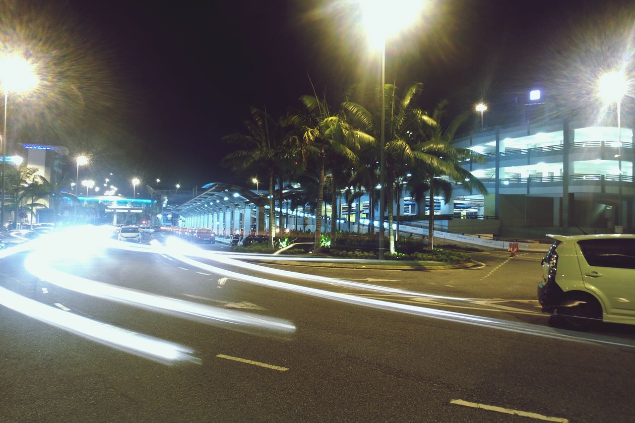 transportation, car, land vehicle, mode of transport, street, road, illuminated, night, lens flare, city, building exterior, street light, sunbeam, architecture, built structure, sunlight, the way forward, sun, city street, road marking