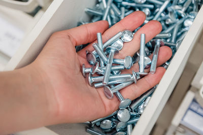 A lot of bolts in the palm of your hand. storage of screws in the store and at home