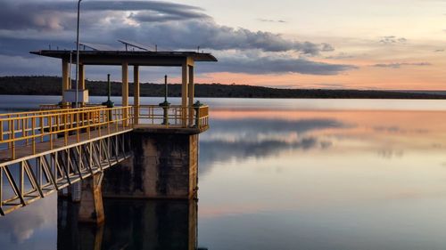 Pier on lake against sky during sunset