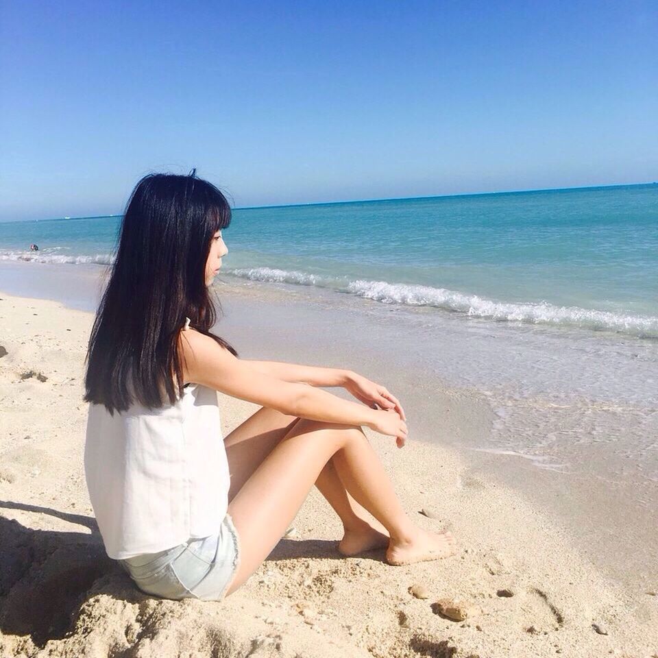 sea, beach, horizon over water, sand, shore, sitting, one person, real people, nature, scenics, beauty in nature, water, tranquil scene, leisure activity, outdoors, tranquility, sky, full length, sunlight, day, lifestyles, clear sky, vacations, young adult, young women, beautiful woman, people