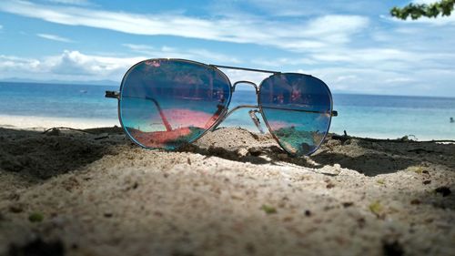 Sunglasses on beach against sky