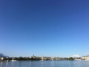 Sea by city against clear blue sky