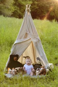 Full length of baby boy with toys in tent on grass