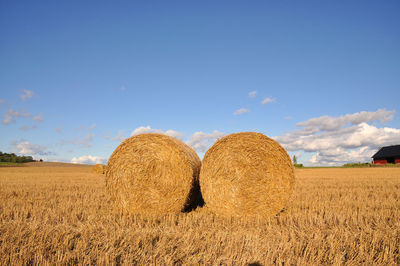 Hay bales on field against sky