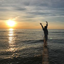 Silhouette man standing on beach against sky during sunset