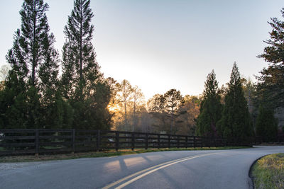 Diminishing perspective of empty road passing through forest at sunset