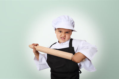 Portrait of boy standing against gray background