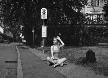 Woman sitting on footpath in city