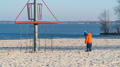 Rear view full length of boy standing by structure at beach