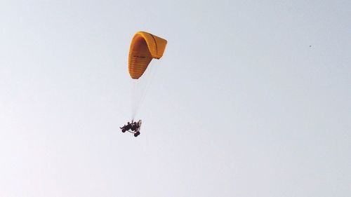 Low angle view of person paragliding against clear sky