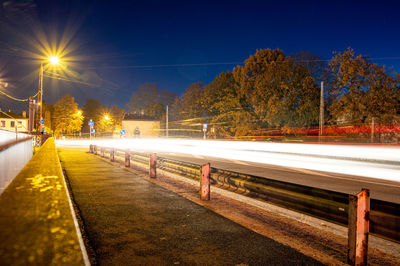 Light trails on street against sky at night