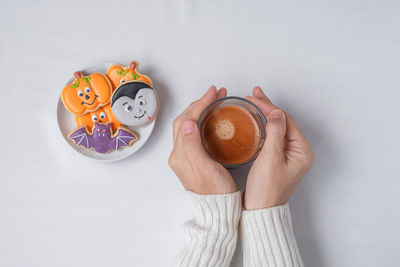 Directly above shot of hand holding coffee cup against white background