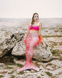 Portrait of young woman standing on rock at beach