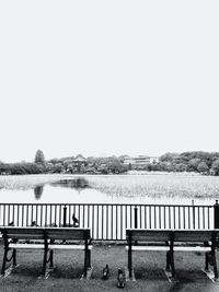 Empty bench in front of lake against clear sky