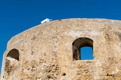 Low angle view of old building against clear blue sky