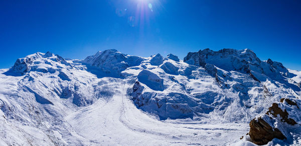 Low angle view of a glacier and snowcapped mountains against clear blue sky