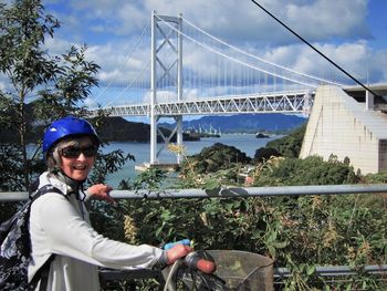 Portrait of smiling man riding bridge against sky