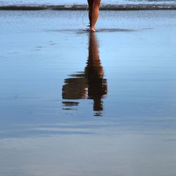 Low section of woman standing at beach