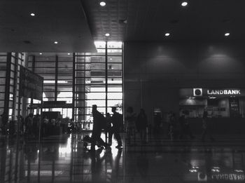 Silhouette people walking in illuminated airport