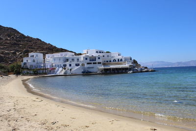 Buildings by sea against clear sky