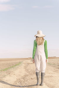 Young woman looking at dry field dry field, rear view