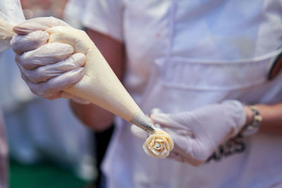 Midsection of woman hand making flower with whipped cream