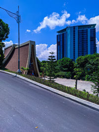 Road by buildings against sky in city