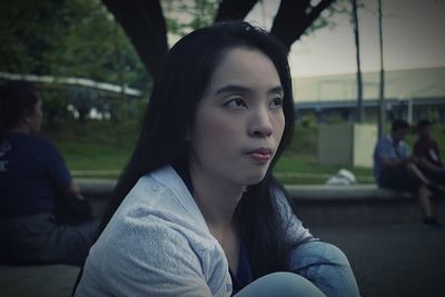 Portrait of young woman sitting at park