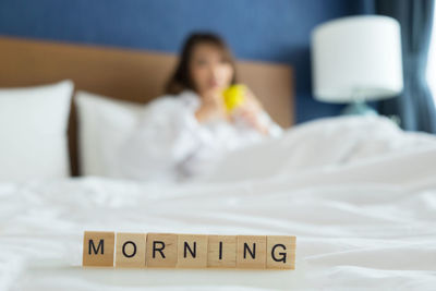 Close-up of morning text with woman in bed at home