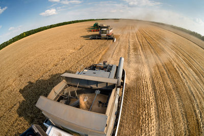 High angle view of combine harvester on wheat field against sky