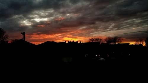 Silhouette buildings against dramatic sky during sunset
