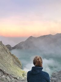 Rear view of woman looking at hot spring view against sky