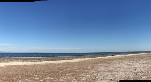 Scenic view of beach against blue sky