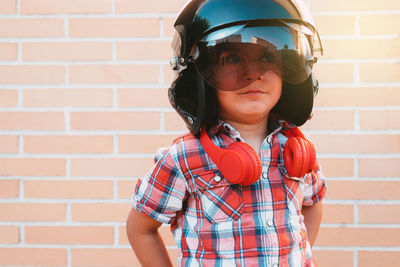 Portrait of boy with russian pilot's helmet on brick wall