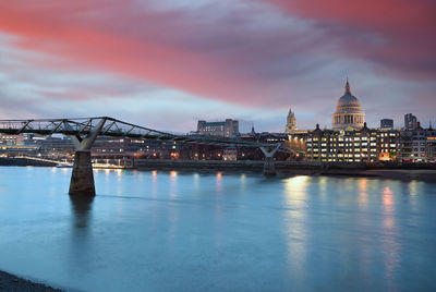 Illuminated bridge over river against sky in city