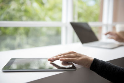 Midsection of man using smart phone on table