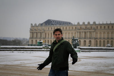 Portrait of man standing against historical building during winter