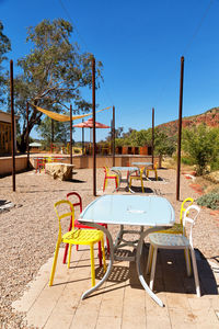 Empty chairs and table at park against clear blue sky