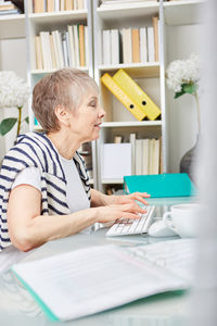 Side view of woman using computer at home