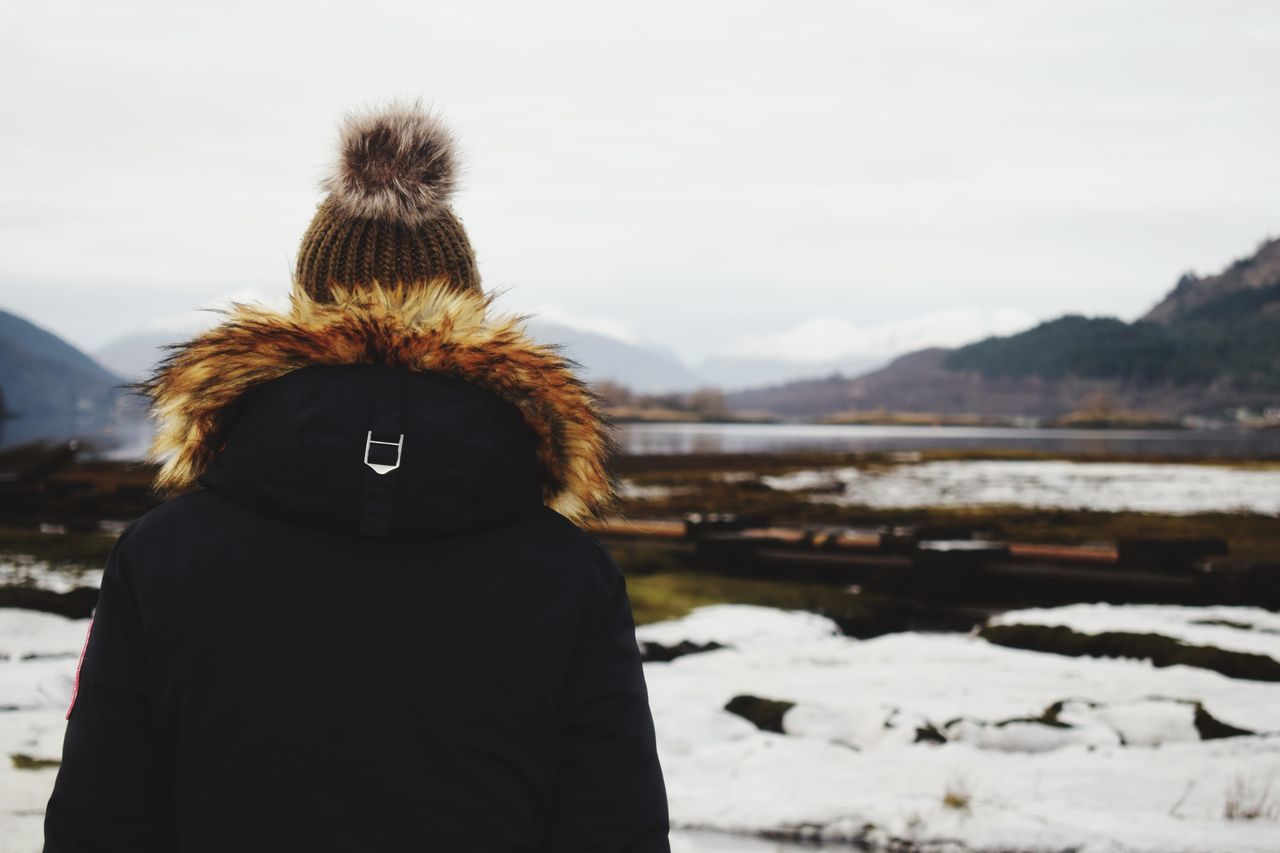 rear view, real people, sky, focus on foreground, one person, outdoors, day, leisure activity, standing, lifestyles, mountain, warm clothing, winter, nature, women, close-up, young adult, people