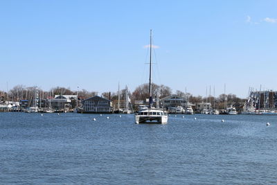 Sailboats moored on sea against clear blue sky